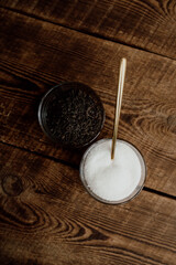 Glass bowls with tea and sugar and golden spoon on wooden background. Ingredients for homemade kombucha fermented tea top view