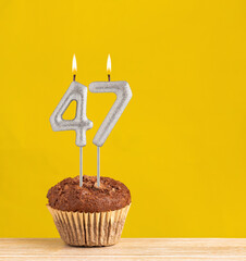 Chocolate cupcake with number 47 candle - Birthday on a yellow background.