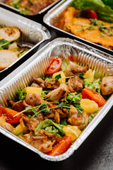 Fresh and colorful chicken salad with tomatoes and oranges, served in container, healthy takeout