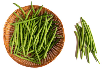 Fresh extra fine long green beans topped in a cane basket on white background