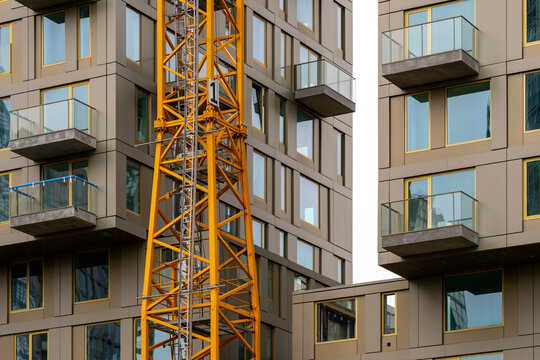 An image depicting a close-up view of a construction crane in front of a glass building facade, symbolizing industrial progress and the growth of urban architecture in Rotterdam