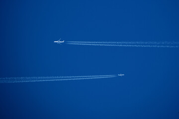 Airplanes in the blue sky with contrails. Shallow depth of field.