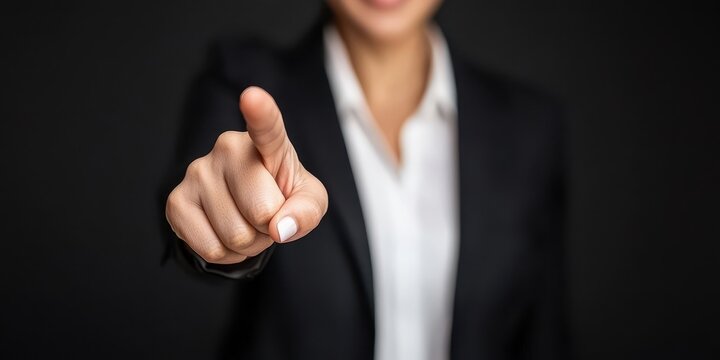 Confident businesswoman pointing finger towards the camera indicating authority.