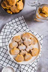 Homemade pumpkin shaped cookies in powdered sugar on a plate top and vertical view