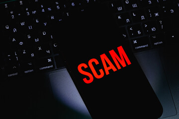 smartphone with red text SCAM on a black screen