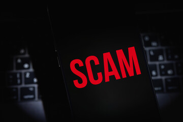 mobile smartphone with red text SCAM on a black screen