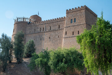 A large castle sits atop a hill, surrounded by trees and greenery, Shush, Iran