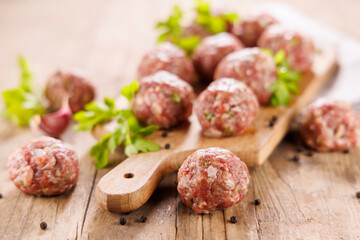raw meatballs on wooden board with herbs