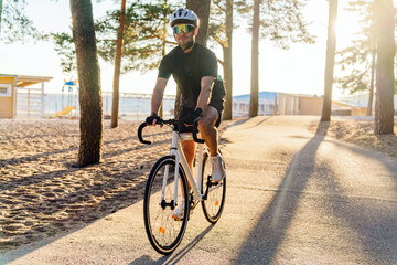 Naklejka premium A Cyclist Rides Along a Sandy Path Surrounded by Trees During a Golden Hour at the Beach