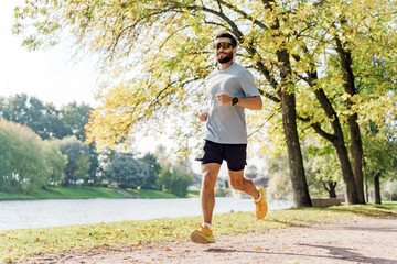 A Man Jogging by a Serene Lake Surrounded by Vibrant Trees on a Sunny Day in a City Park