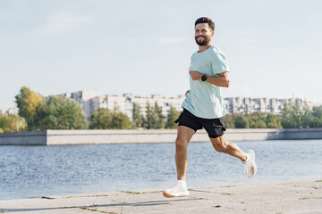 A Man Jogs Along the Riverside Pathway in the Afternoon, Enjoying a Sunny Day in a Vibrant City