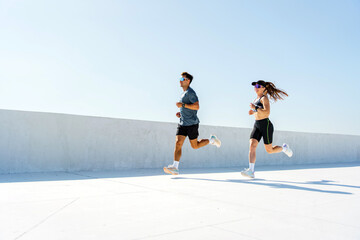 Two Runners Jogging on a Sunny Day Along a White Minimalist Surface in an Urban Setting