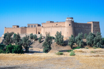 A large castle sits atop a hill, surrounded by trees and greenery, Shush, Iran