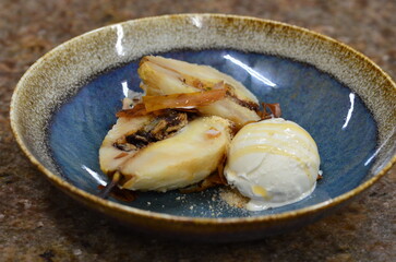 baked pear in dough, served dessert on a plate, behind a marble table