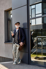 A fashionable senior man stands confidently by a modern building, exuding charm with his stylish attire.