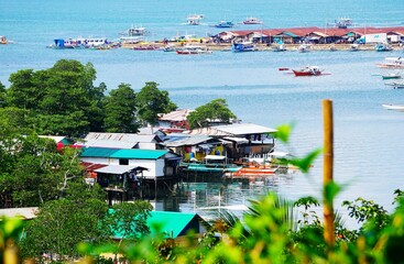 Wioska rybacka na wodzie. Domy usytuowane na wodzie. Niewielkie domki na wybrzeżu, łodzie rybackie, dzika natura i góry. Życie na Filipinach na wyspie Palawan. © Adam