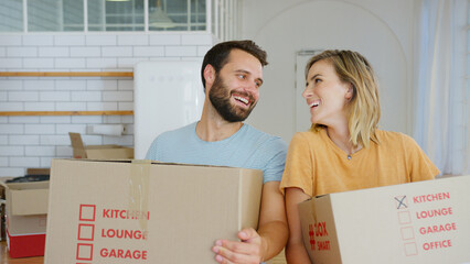 Portrait Of Smiling Young Couple Carrying Packing Boxes Moving Into New Home 