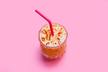Ice Thai tea with milk on pink background.