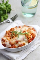 Delicious al forno pasta in baking dish on light table