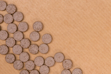 Close up of brown pills on wooden background. Selective focus.