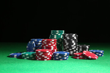 Poker chips on green table against dark background
