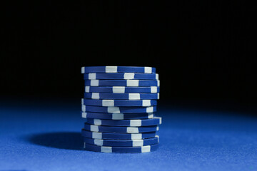 Poker game. Casino chips on blue table against dark background