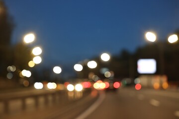 Blurred view of cityscape with road traffic and street lights in evening