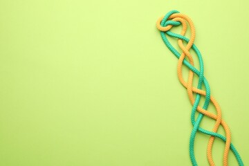 Braided colorful ropes on green background, top view with space for text. Unity concept