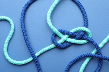 Colorful ropes tied in knot on blue background, top view. Unity concept