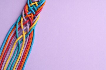 Colorful ropes tied together on violet background, top view and space for text. Unity concept