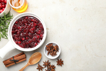 Tasty cranberry sauce in gravy boat, honey, spices and berries on light table, flat lay. Space for text