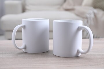 Blank ceramic mugs on white wooden table. Mockup for design