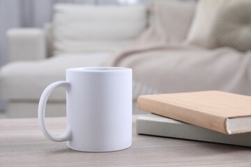 Blank ceramic mug and notebooks on wooden table. Mockup for design
