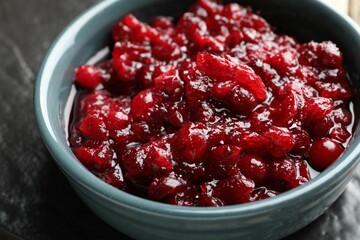 Tasty cranberry sauce in bowl on table, closeup