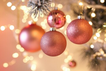 Pink Christmas ornaments hanging on a tree with lights