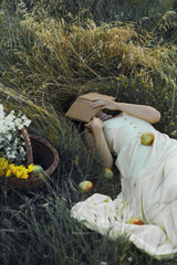 Woman resting in the green grass, hiding her face with a book.