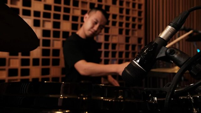 Young musician passionately playing drums in a contemporary music studio, creating vibrant rhythms and exploring artistic expression through sound and creativity.