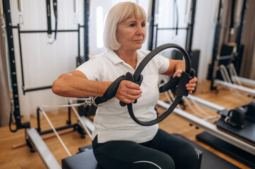 Senior woman is in the gym, with training equipment