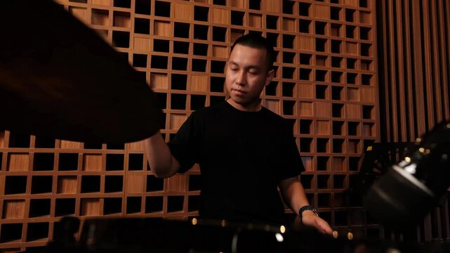 Young Male Drummer Playing Energetically in Modern Recording Studio Surrounded by Wood Panels and Professional Equipment for Music Production
