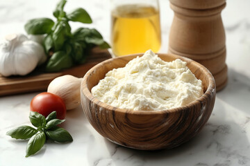 Fresh ricotta cheese served in a wooden bowl with basil, garlic, tomatoes, and olive oil on a marble countertop. Generative AI