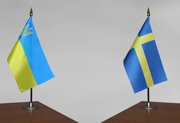 Table flags of Ukraine and Sweden on a gray blurred background