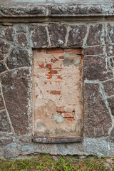 Weathered brick and stone wall with walled up window showcasing rustic texture