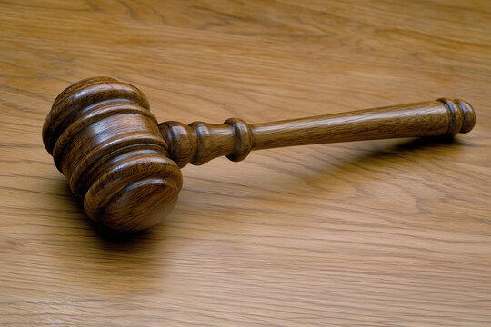 A wooden gavel resting on a polished surface, symbolizing justice and authority in a courtroom setting. Generative AI