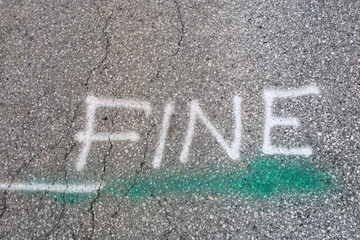 Parola Fine scritta con vernice bianca in stampatello su asfalto grigio