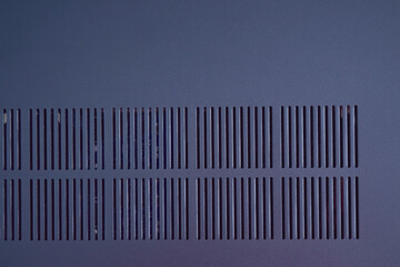 Close-up view of modern ventilation slits on a metallic blue surface, creating a sleek and...