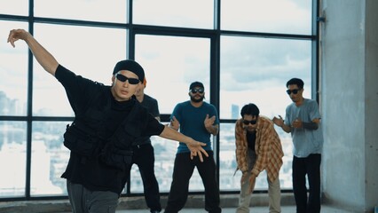 Multicultural hipster group looking at camera while perform break dancing at building with sky scrapper or city view. Street dancer team looking at dancer performance. Outdoor sport 2024. Hiphop.