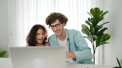 Caucasian dad put headphones on daughter while girl learning code. Father take care schoolgirl...