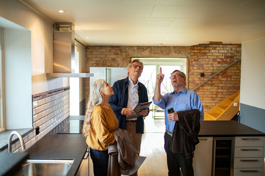 Elderly couple consulting with real estate agent in new home kitchen