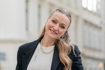 Portrait of smiling beautiful woman 35-40 years old on blurred city background.