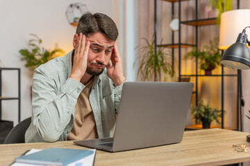 Angry furious man freelancer using laptop while working at home office having nervous breakdown at work, stress management, mental distress problems, losing temper, reaction on failure. Lifestyle